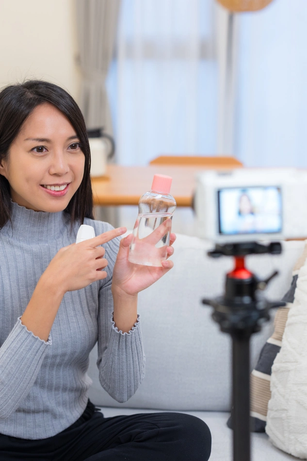 Woman recording brand video to promote skincare product for social media marketing campaign.