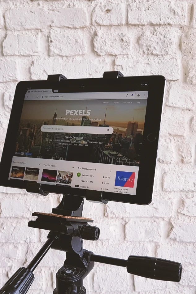 Tablet mounted on tripod showing a stock photo platform, used in planning stages of corporate video services.